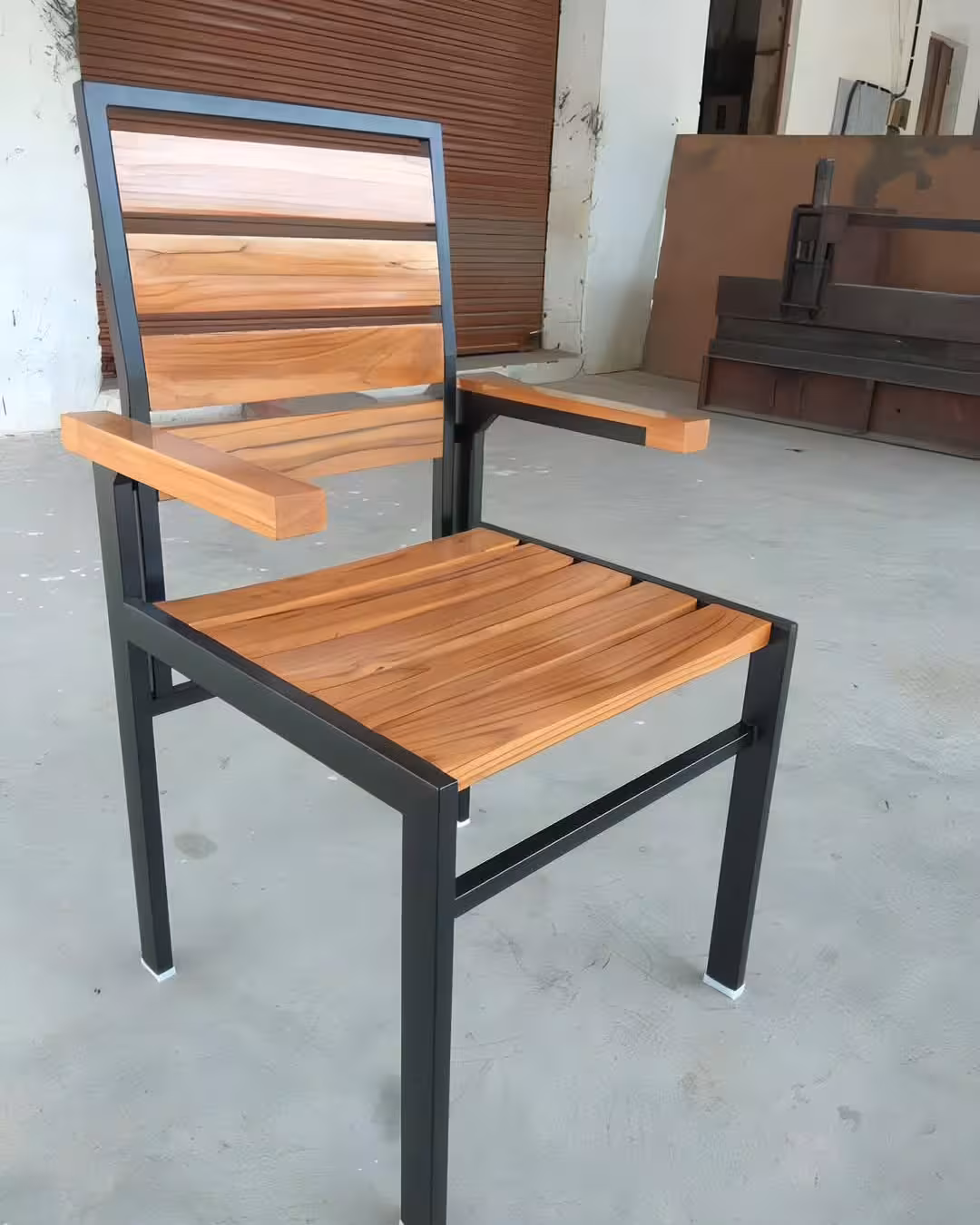 A robust industrial-style armchair combining a matte black metal frame with natural multi-tonal wood slats for a modern loft aesthetic.